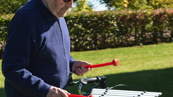 Cadenza Outdoor Music Instrument (older man playing; right side view)