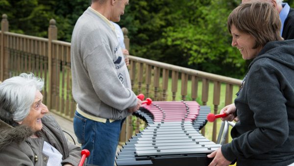Duo Outdoor Music Instrument (older woman playing with family; side view)