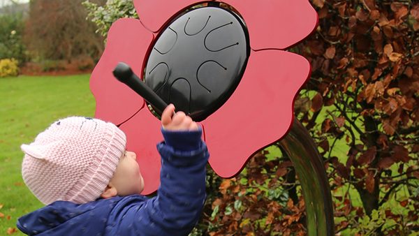 Percussion Play Poppy Petal Drum (small child playing; side view)