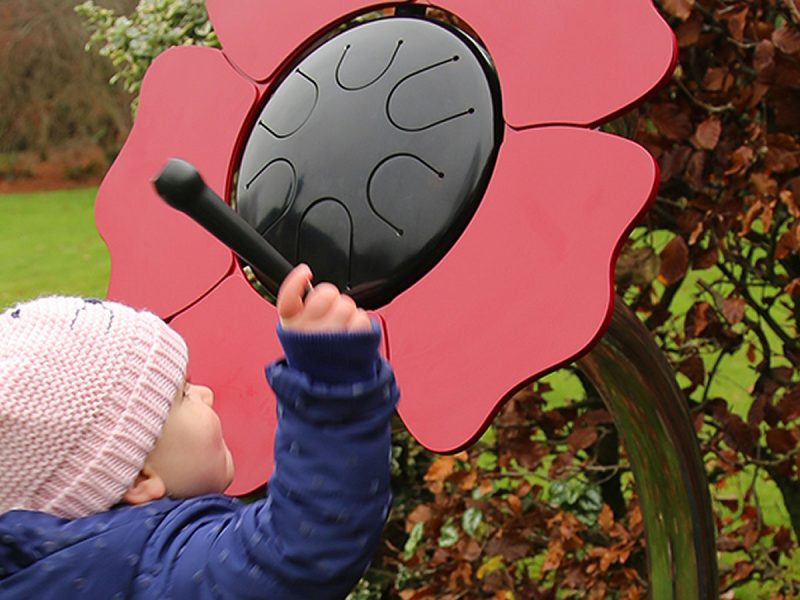 Percussion Play Poppy Petal Drum (small child playing; side view)
