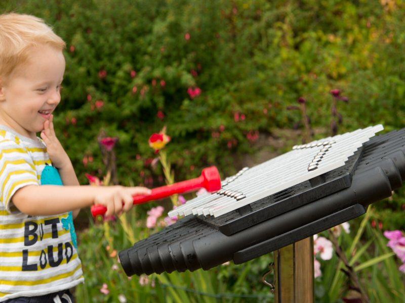 Sansa Rimba Outdoor Music Instrument (young boy playing; side view)